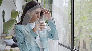 Young businesswoman enjoying her morning coffee or tea, looking out the window. Beautiful latina woman