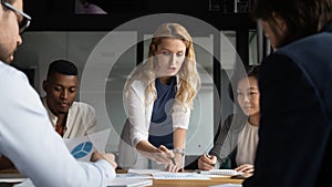 Young businesswoman explaining research results in graphs to colleagues.