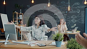 Young businesswoman expressing happiness over good news in office while colleagues applauding