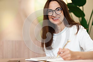 Young businesswoman in eyeglasses planning and writing down the daily schedule with in agenda