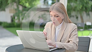 Young Businesswoman Feeling Shock while using Laptop in Outdoor Cafe