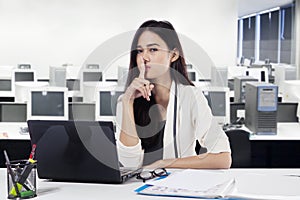Young businesswoman gesturing silence in the office