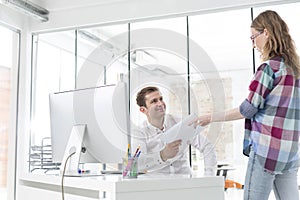 Young businesswoman giving documents to colleague at office