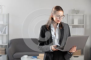 Young businesswoman in glasses working on laptop with too much work in office. Secretary girl.