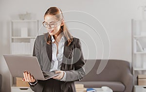 Young businesswoman in glasses working on laptop with too much work in office. Secretary girl.