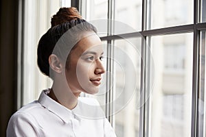 Young businesswoman with hair bun looking out of window