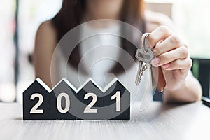 Young Businesswoman hands holding key and 2021 Happy New Year with house model on table office. New House, Financial, Property