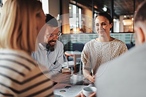 Young businesswoman having coffee with coworkers