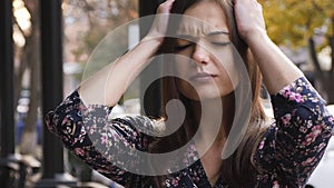 Young businesswoman with headache, a girl is standing on the street tired and painful.