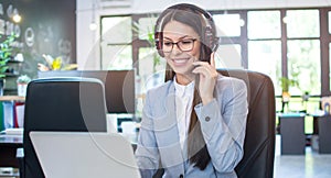 Young businesswoman with headset working on laptop in modern office