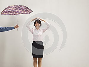 Young businesswoman with her hand above head, co-worker giving her umbrella