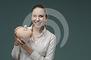 Young businesswoman holding a clay money box