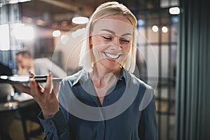 Young businesswoman laughing and talking on speakerphone in an o