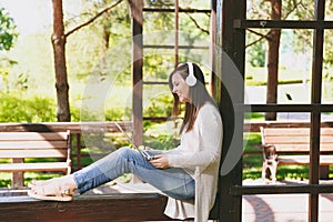 Young businesswoman in light casual clothes. Woman working on modern laptop pc computer, listen music in headphones on