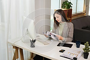 Young businesswoman looking at computer screen, working distantly at modern home office