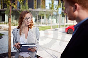 Young businesswoman looking seductively  her interlocutor outdoor in front of business building. outdoor, unofficial, meeting, photo