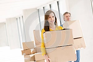 Young businesswoman with male colleague carrying cardboard boxes in new office