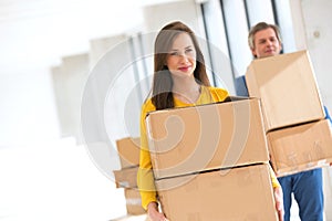 Young businesswoman with male colleague carrying cardboard boxes in new office