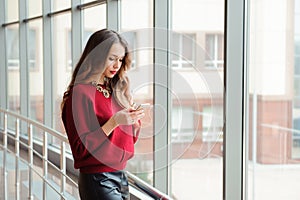 Young businesswoman with mobilephone near the window.