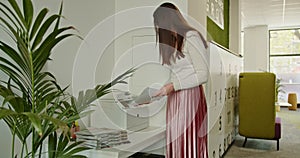 A young businesswoman is photocopying documents on a copier in a well organized and contemporary office setting.