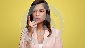 Young businesswoman in pink suit on yellow background