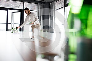 Young businesswoman placing water bottles on conference table in office