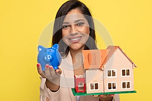 Young businesswoman presenting piggy bank and house model