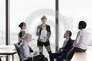 Young businesswoman presenting project report to different aged diverse team