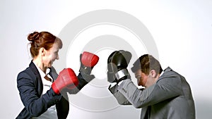 Young businesswoman punching colleague with boxing gloves