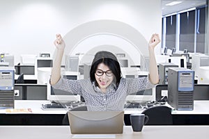 Young businesswoman raising hands on office