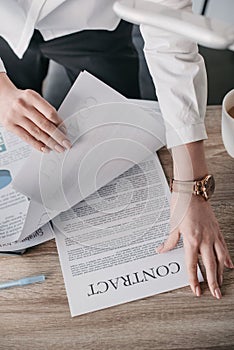 Young businesswoman reading contract documents in office