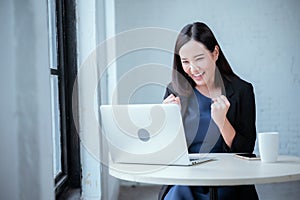 Young businesswoman rejoicing after sales surpass their target Check results from laptop