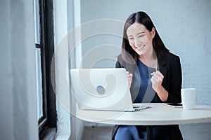 Young businesswoman rejoicing after sales surpass their target Check results from laptop photo