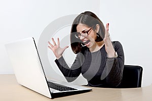 Young businesswoman screaming at laptop