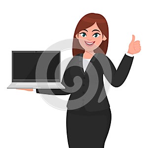 Young businesswoman showing a new brand laptop and making thumb up gesture sign. Person holding portable computer.