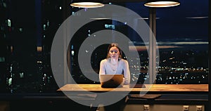 Young businesswoman sit at workplace working on laptop until late