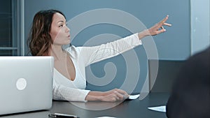 Young businesswoman sitting on business meeting with colleagues in office, asking questions