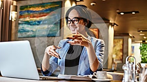 Young businesswoman sitting in cafe in front of laptop and networking