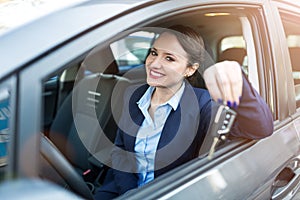 Young businesswoman sitting in car holding car keys