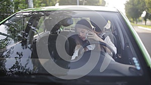 Young businesswoman sitting into the car, speaking on the phone and flirting