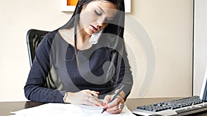 Young businesswoman sitting at desk in office busy on phone
