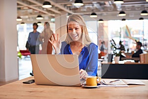 Young Businesswoman Sitting At Desk On Video Call In Modern Open Plan Office