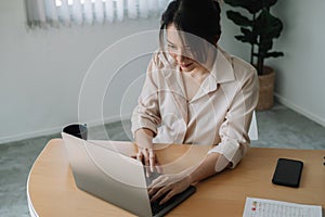 Young businesswoman sitting front open portable laptop computer reading email from client, long hours of work concept.