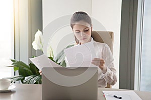 Young businesswoman sitting at office desk working, looking thro