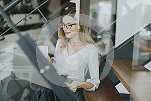 Young businesswoman sitting oh the office stairs and having coffee break