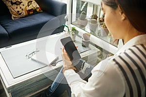 Young businesswoman sitting in workplace and using mobile phone