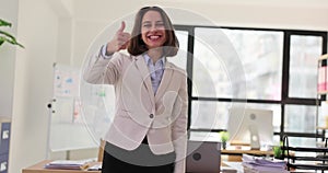 Young businesswoman smiling and showing thumbs up in office