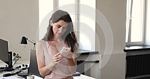 Young businesswoman standing alone at workplace use smartphone