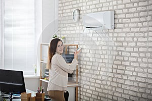 Businesswoman Using Remote Control Of Air Conditioner