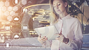 Young businesswoman stands and uses digital.In foreground are virtual icons with clouds, people, digital gadgets.